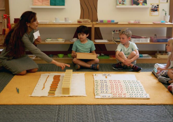 Teacher observing students as they explore Montessori activities independently.