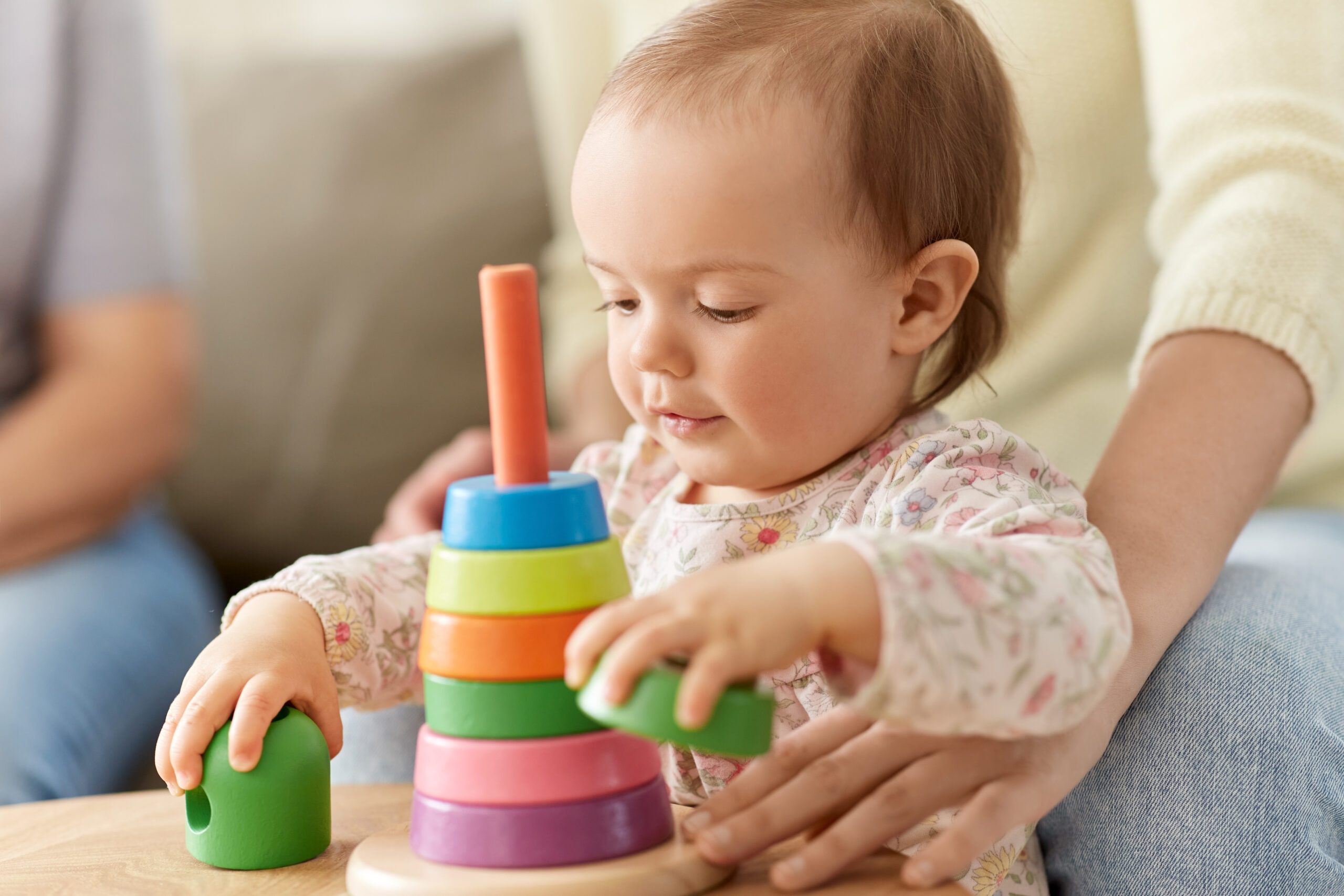 childhood and developing concept - lovely baby girl playing with toy pyramid at home